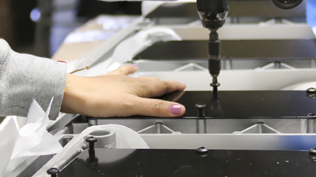 Worker performing light assembly services including packaging and component assembly.