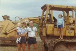 Historical photo of Techno-Coat founders in 1983, standing in front of earth moving equipment at groundbreaking.