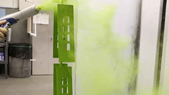 Parts being powder coated in a spray booth